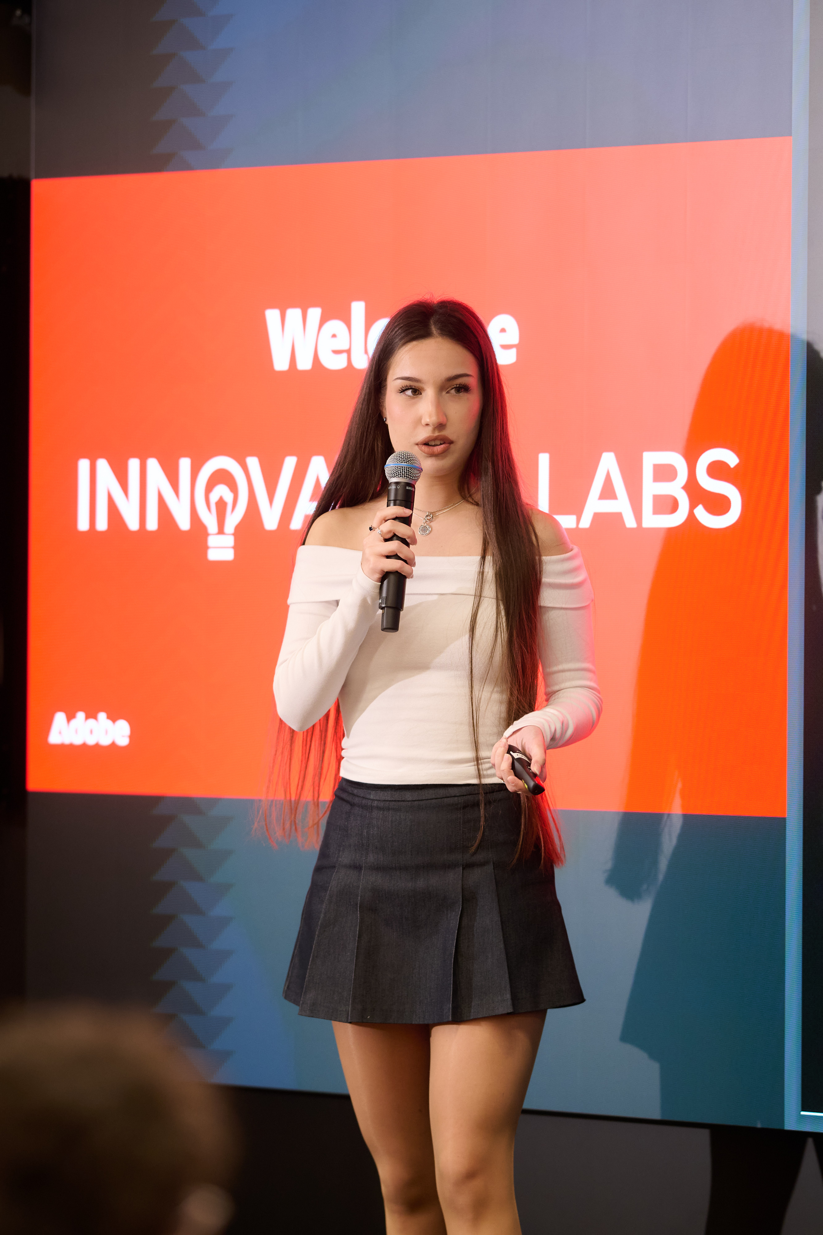 Alexandra pitching with a microphone in front of an Innovation Labs slide